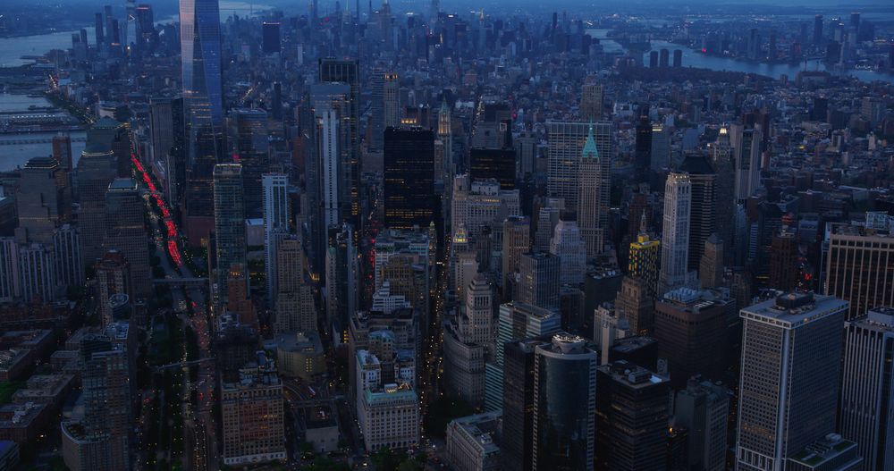 Wall Street Office Buildings at Night: Scenic Aerial New York City View of Lower Manhattan Architecture. Panoramic Financial District Image from a Helicopter. Evening Cityscape with Skyscrapers