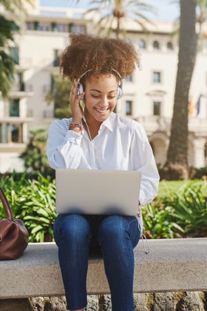 Smiling Black woman with netbook and headphones on street