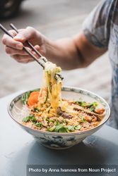 Man eating noodles at Vietnamese restaurant with chopsticks 0ggal0
