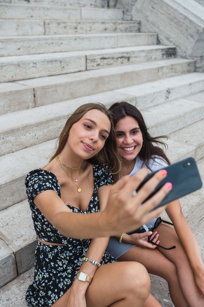 Laughing women taking selfie on stairs at old building