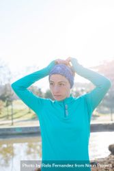 Woman in ear warmers adjusting hair while working out outdoors on sunny fall day 0Wwor0