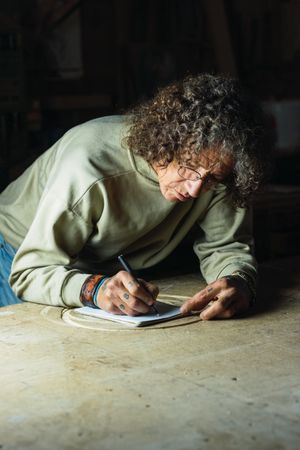 Male carpenter creating sketch in notebook in workshop