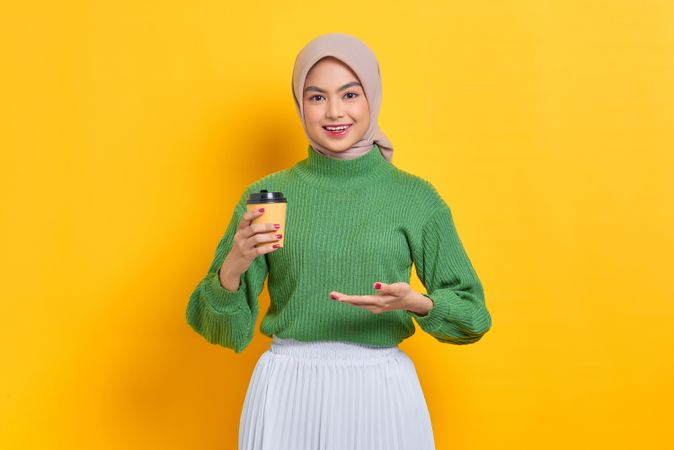 Woman in headscarf holding to go coffee cup