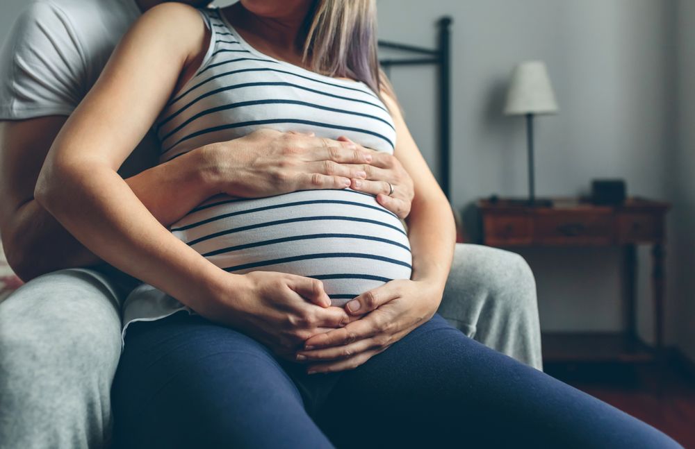 Pregnant woman embraced by her husband