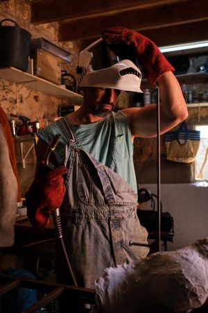 Male artisan putting on welding helmet