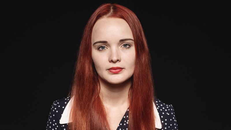Portrait of a woman with long reddish brown hair isolated on dark background