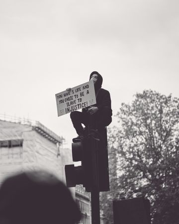 London, England, United Kingdom - June 6th, 2020: Man with sign atop traffic light at BLM protest