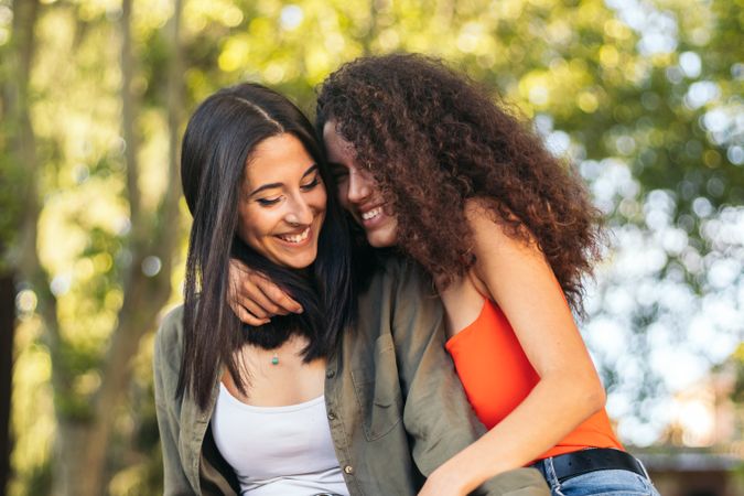 young female couple sitting hugging in a park