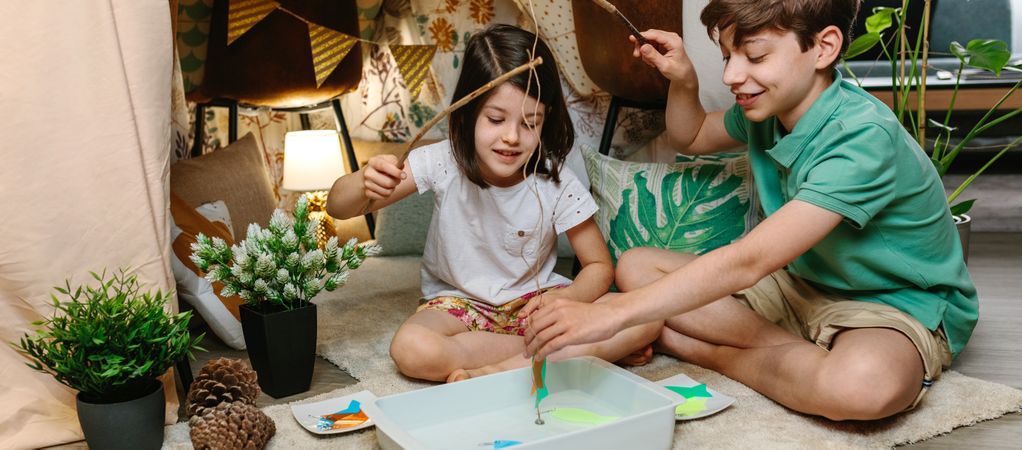 Children camping at home playing fishing game