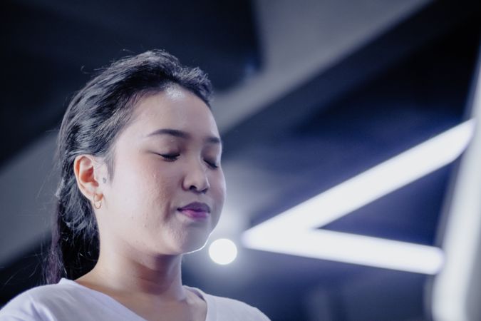 Contemplative Asian Woman Meditating Under Modern Lighting Design