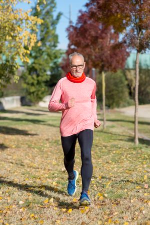 Male jogging through autumn leaves in the park