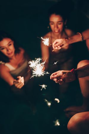 Cheerful friends burning sparkles near pool