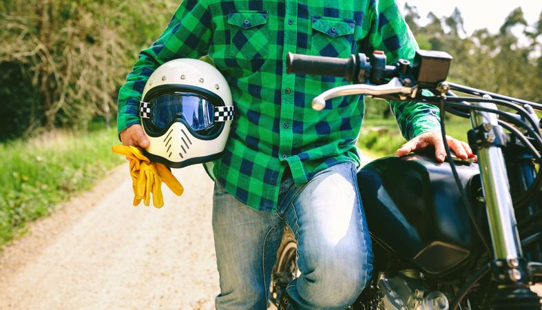 Man posing with motorcycle, helmet and gloves