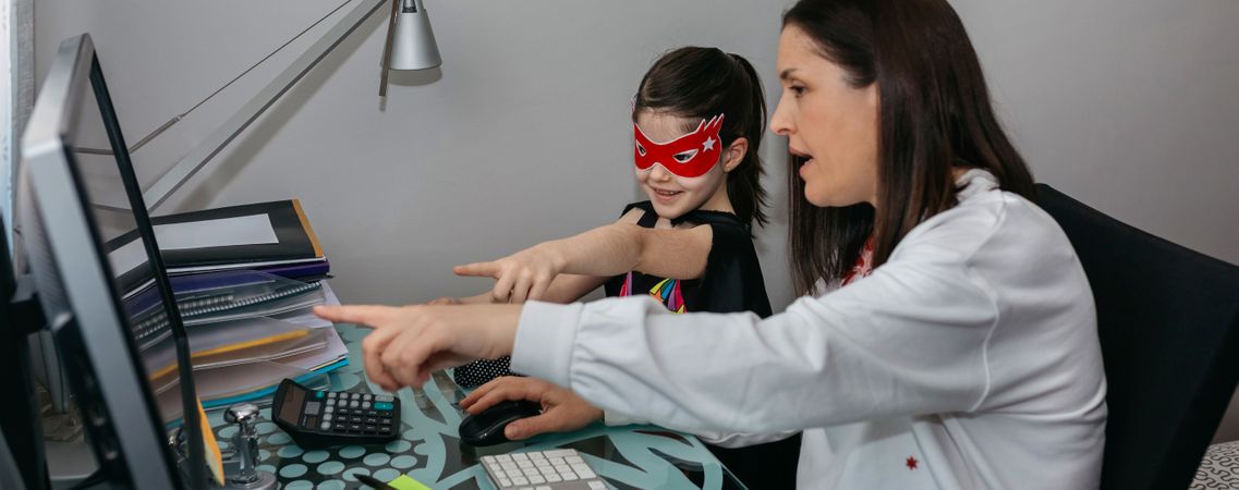 Woman teleworking with daughter showing her a drawing