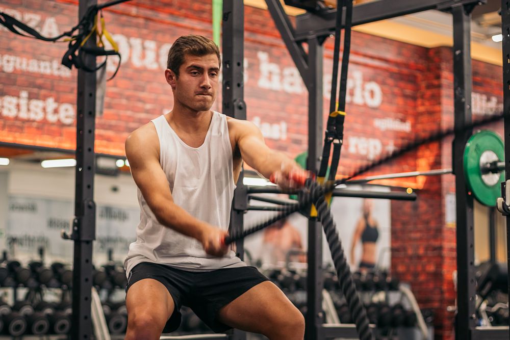 man athlete working out with the ropes in a gym