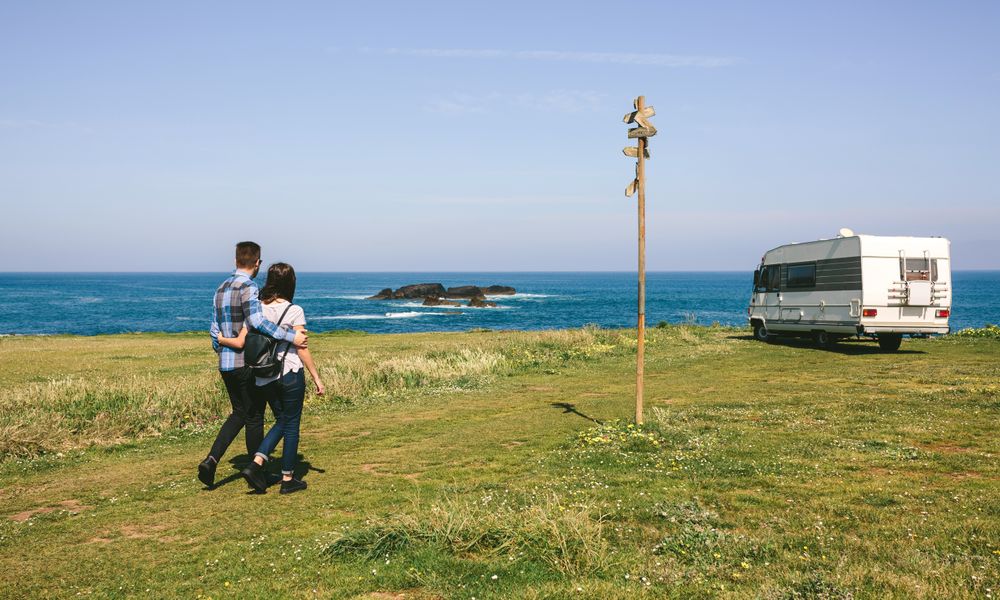 Couple taking a walk near the coast with a camper