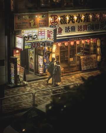 Top view of man and woman walking on sidewalk at night in Japan