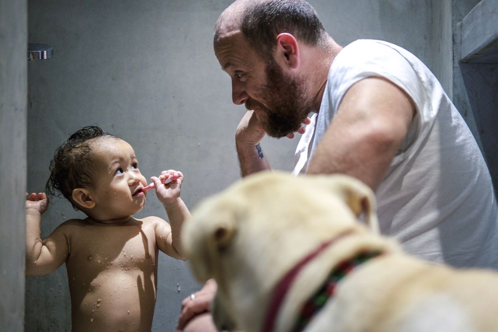 Father looking at his son while brushing his teeth