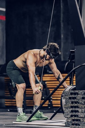 Athletic male pulling ropes in gym