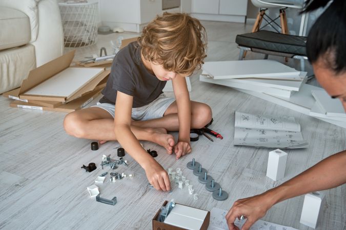 Crop mother and son assembling furniture at home