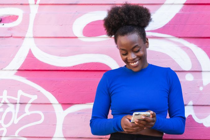 Content Black woman browsing smartphone in city