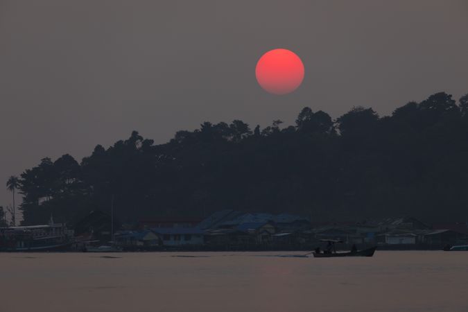 Red bright sun behind rainforest that surrounds small town of Bang Bao, on the island of Koh Chang