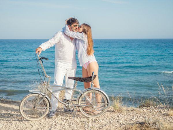 Man and woman holding bicycle at seaside