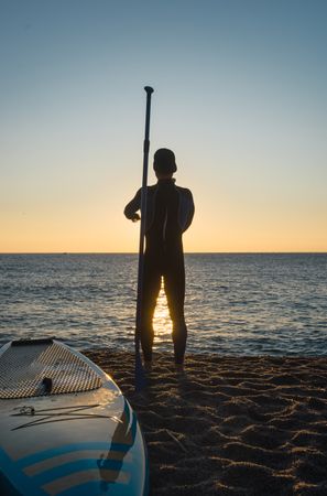 Man practicing paddle surfing with neoprene in a sunrise