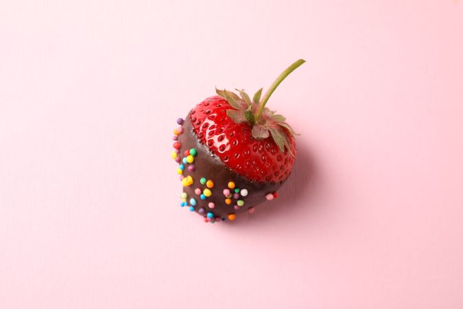 Chocolate fondue. Strawberry in chocolate on pink background