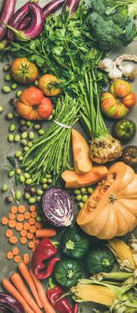Fresh produce on concrete background, with halved squash, corn, cabbage, vertical composition