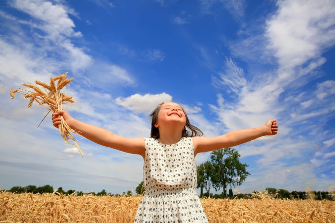 Happy girl with outstretched arms in a wheat field