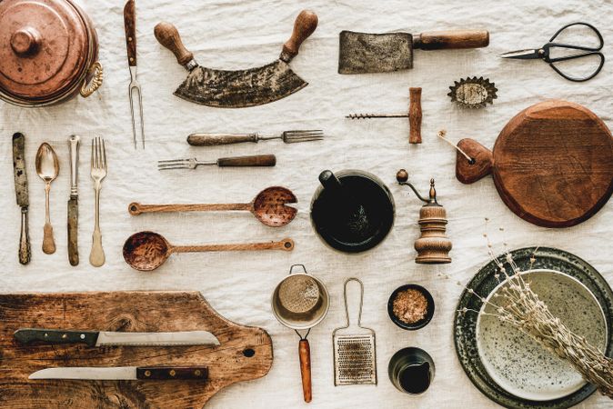 Vintage kitchen utensils, corkscrews, knifes artfully arranged on beige tablecloth