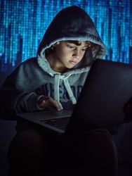 Serious boy using laptop on binary code background