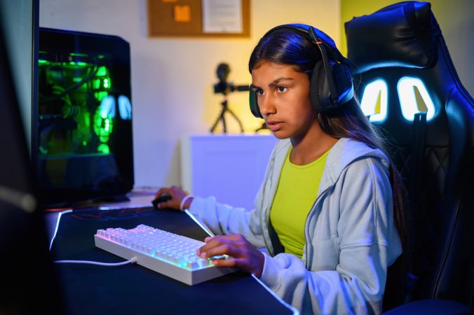 Concentrated young teenage girl sitting at desk and playing games