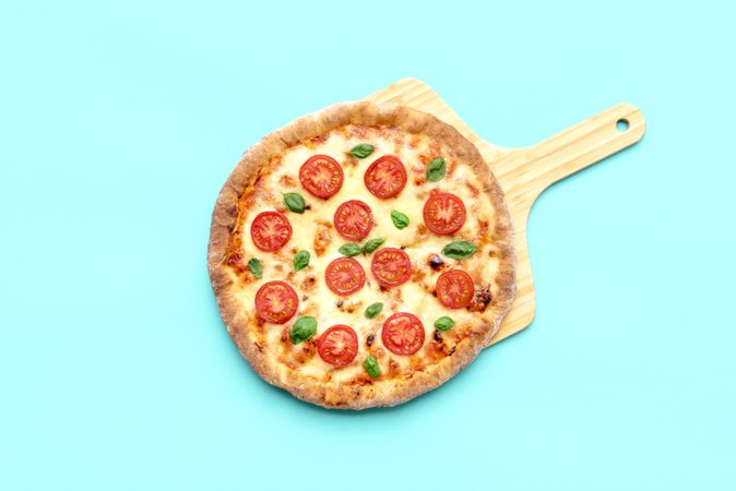 Vegetarian pizza on a wooden board isolated on blue background