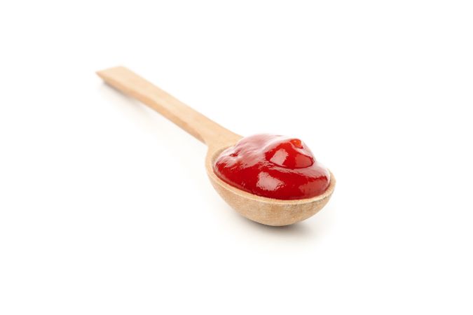 Wooden spoon with tomato sauce isolated on neutral background