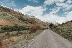 Countryside road on wonderful valley with trees and high hills in cloudy weather
