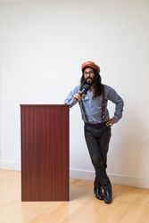 Man leaning on podium with a microphone giving a talk