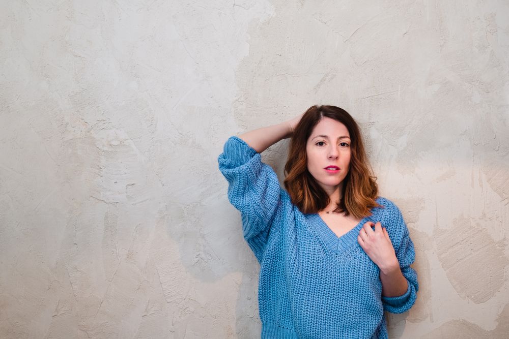 Charming woman in sweater near wall