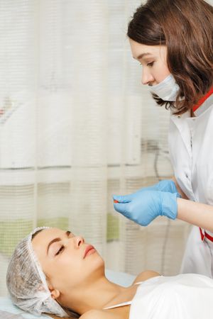 Cosmetologist at med spa prepping female client before treatment, vertical