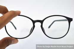 Glasses held by hand on blank background with copy space 0V6anX