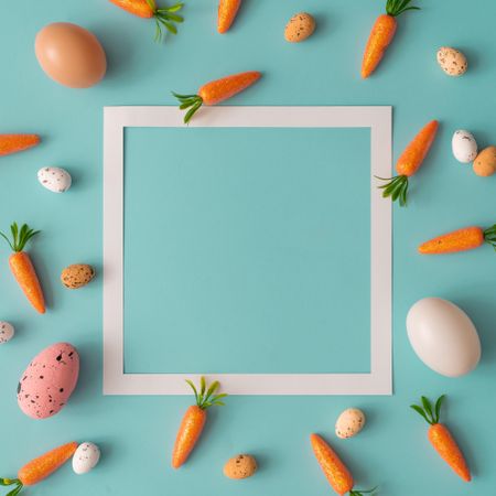 Easter pattern made with carrots on bright blue background with light paper square outline