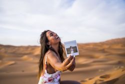 Happy woman showing instant photo in desert