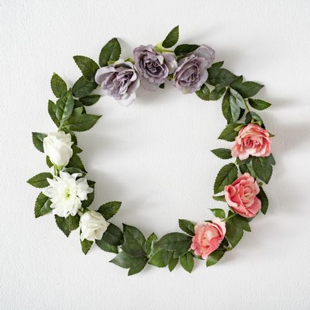 Pink and purple flowers and leaves in wreath on light background