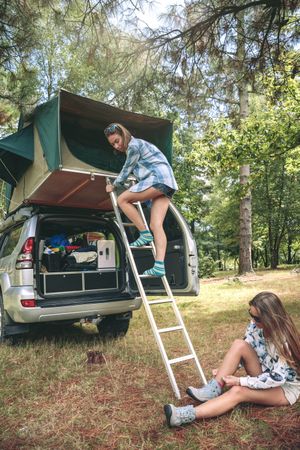 Woman ascending ladder to tent over car
