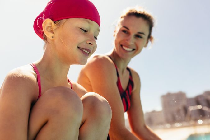 Smiling child with swimming coach beside her