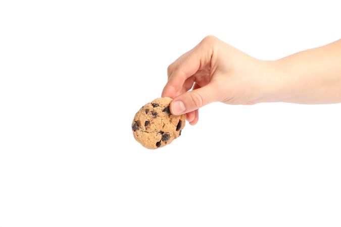 Woman holding tasty chocolate chip cookie on plain background, closeup