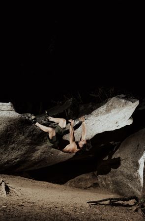 Man practicing rock climbing among large rocks in a forest