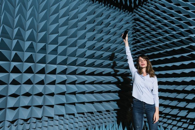 Woman in sound room holding smartphone