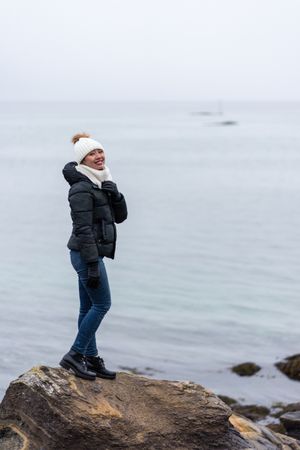 Female standing on stone cliff off coast